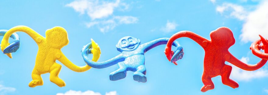 three assorted-color monkey plastic toys holding each other during daytime